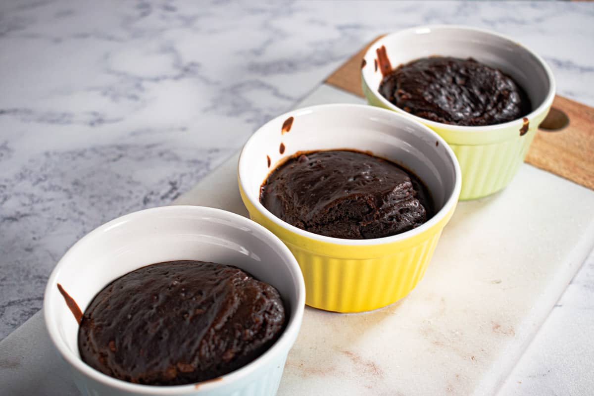 Vegan chocolate lava cakes in multi-coloured ramekins.