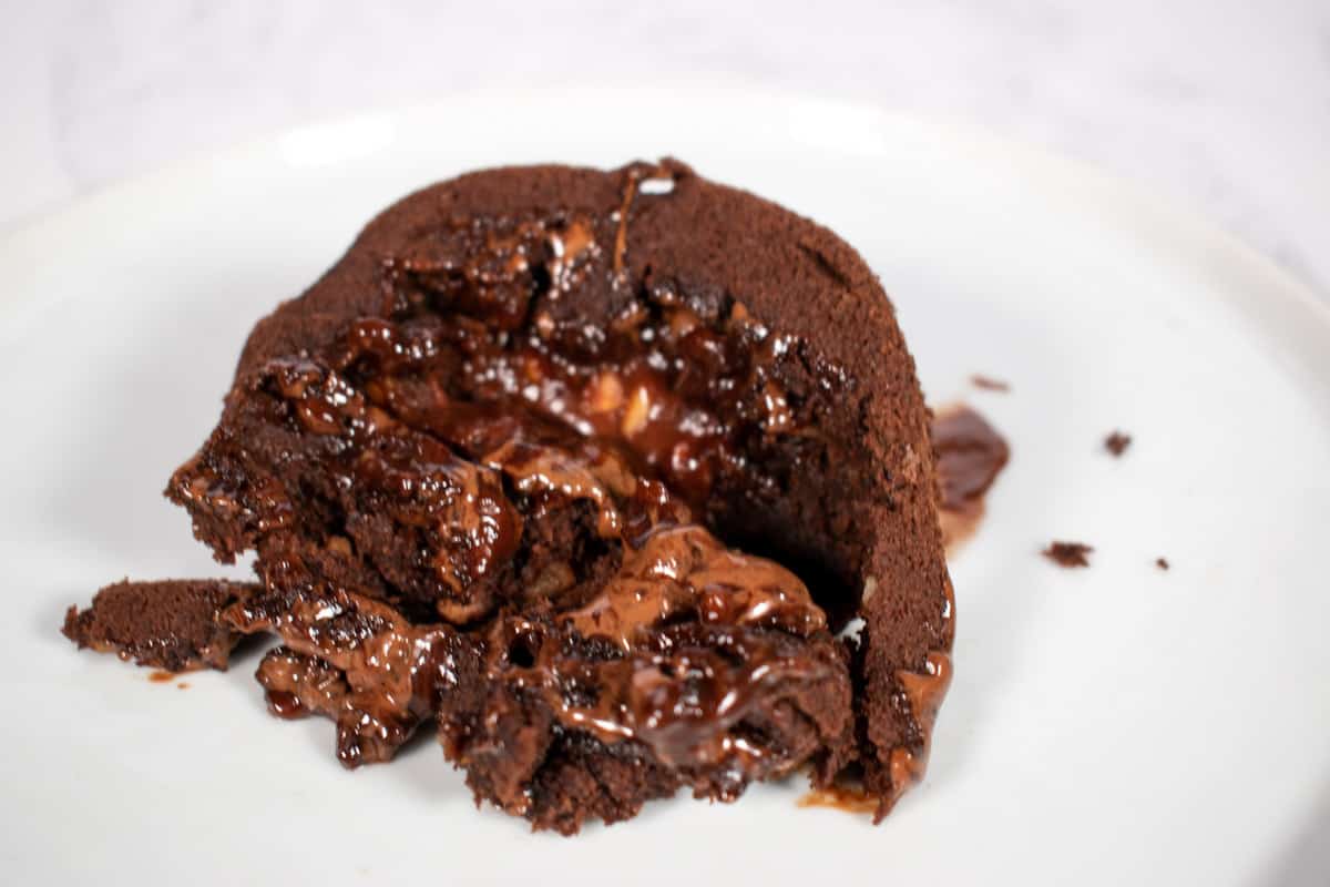 Vegan chocolate lava cake on a white plate. Chocolate drizzling out.