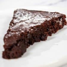 A slice of vegan chocolate cake on a white plate.