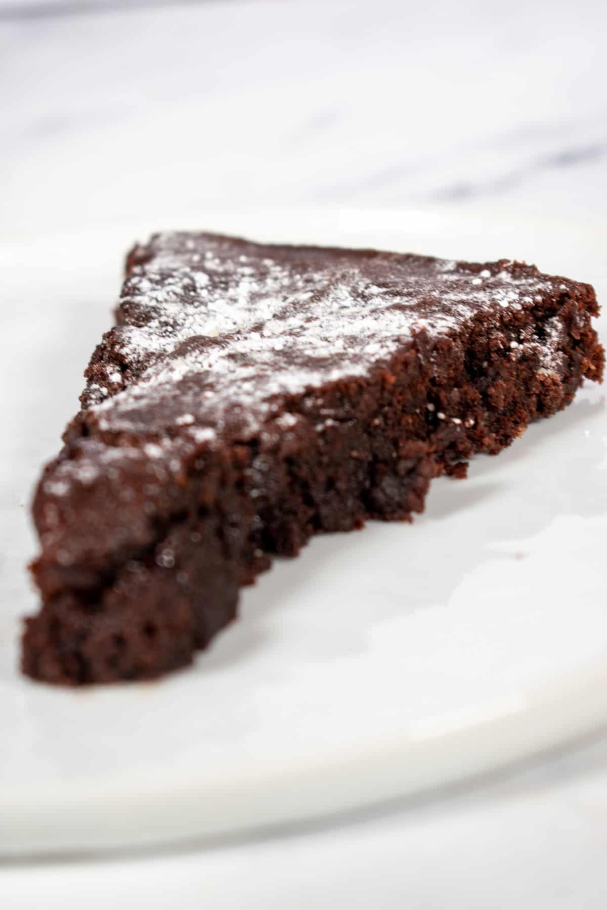 A slice of vegan chocolate cake on a white plate. 