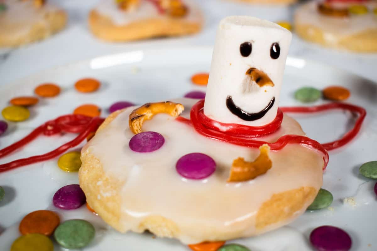 A decorated single vegan melted snowman cookie on a white plate.