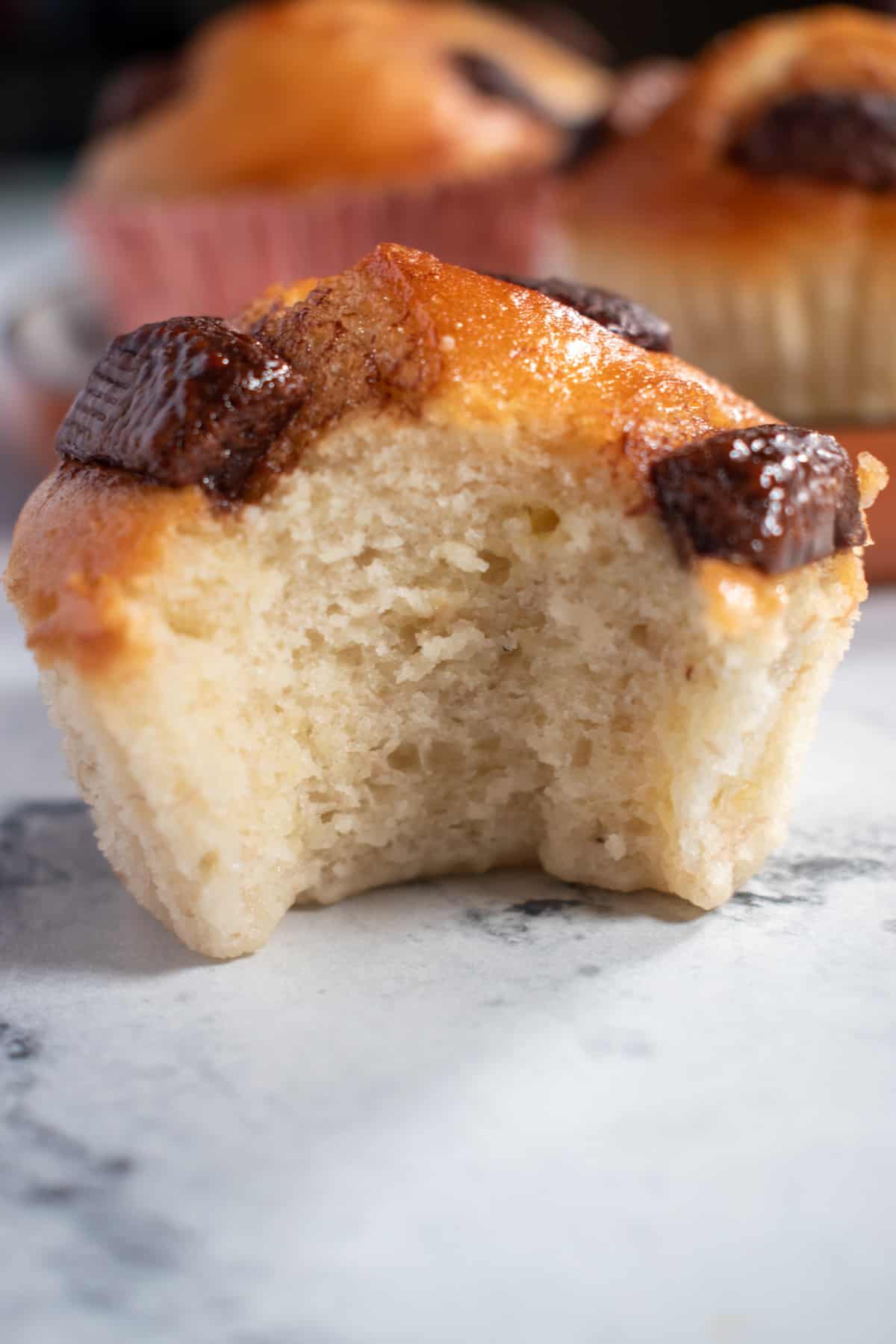 A close up bite shot of a banana muffin. About one quarter has been eaten.