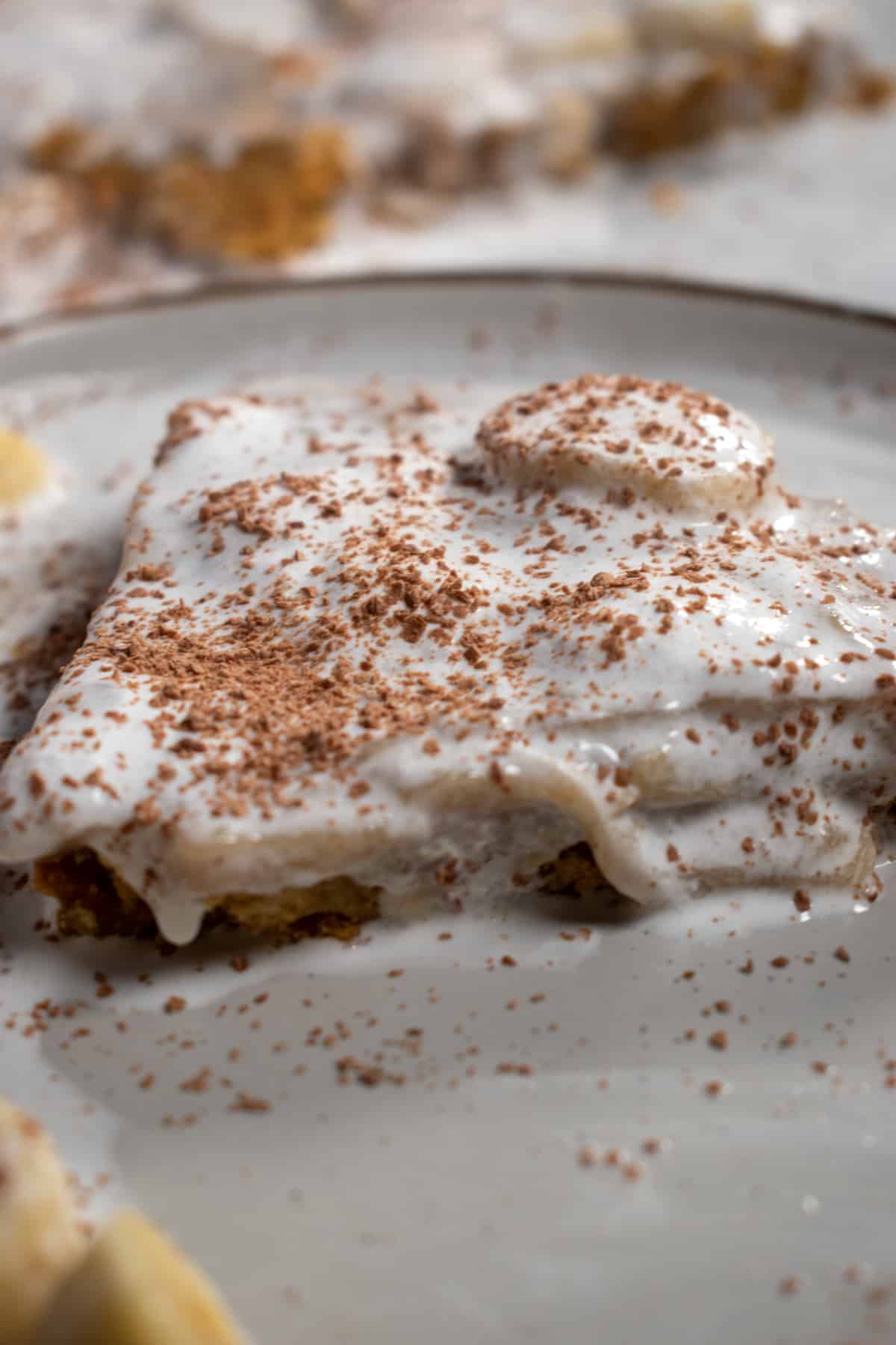 A close up shot of a large slice of vegan banoffee pie on a white plate.