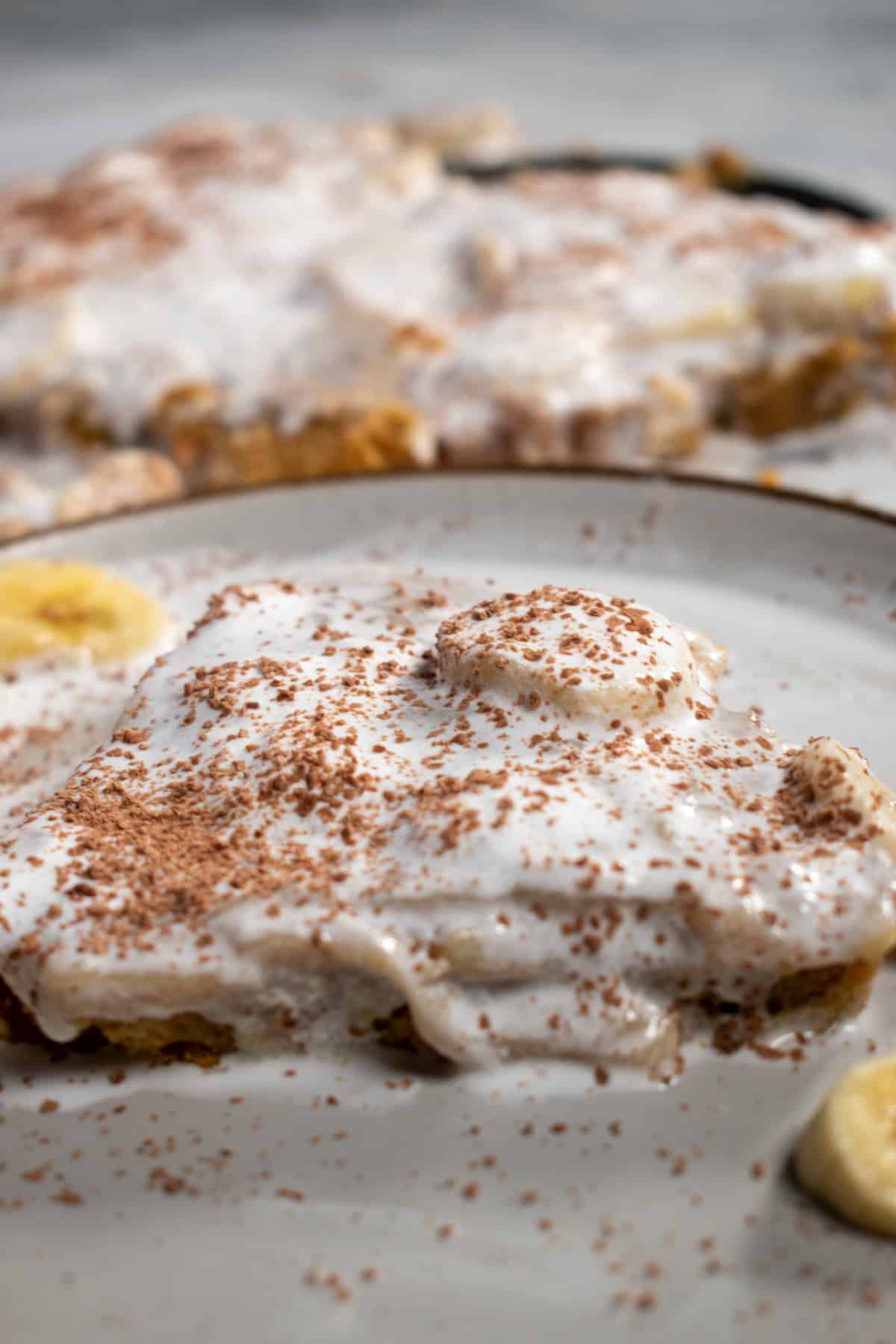 Another close up shot of a large slice of banoffee pie. The rest of the dessert in in the background.