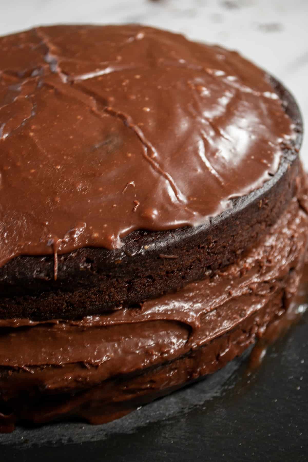 A full, unsliced ganache cake. Lots of creamy chocolate in the middle. 