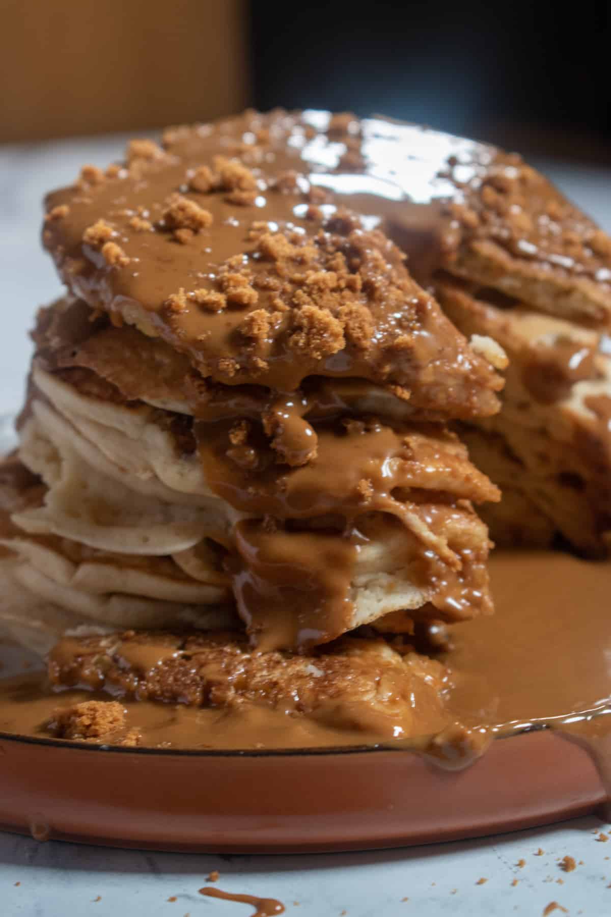 Another side angle of biscoff pancakes. The room is dark and a bright shines over the top of them. 