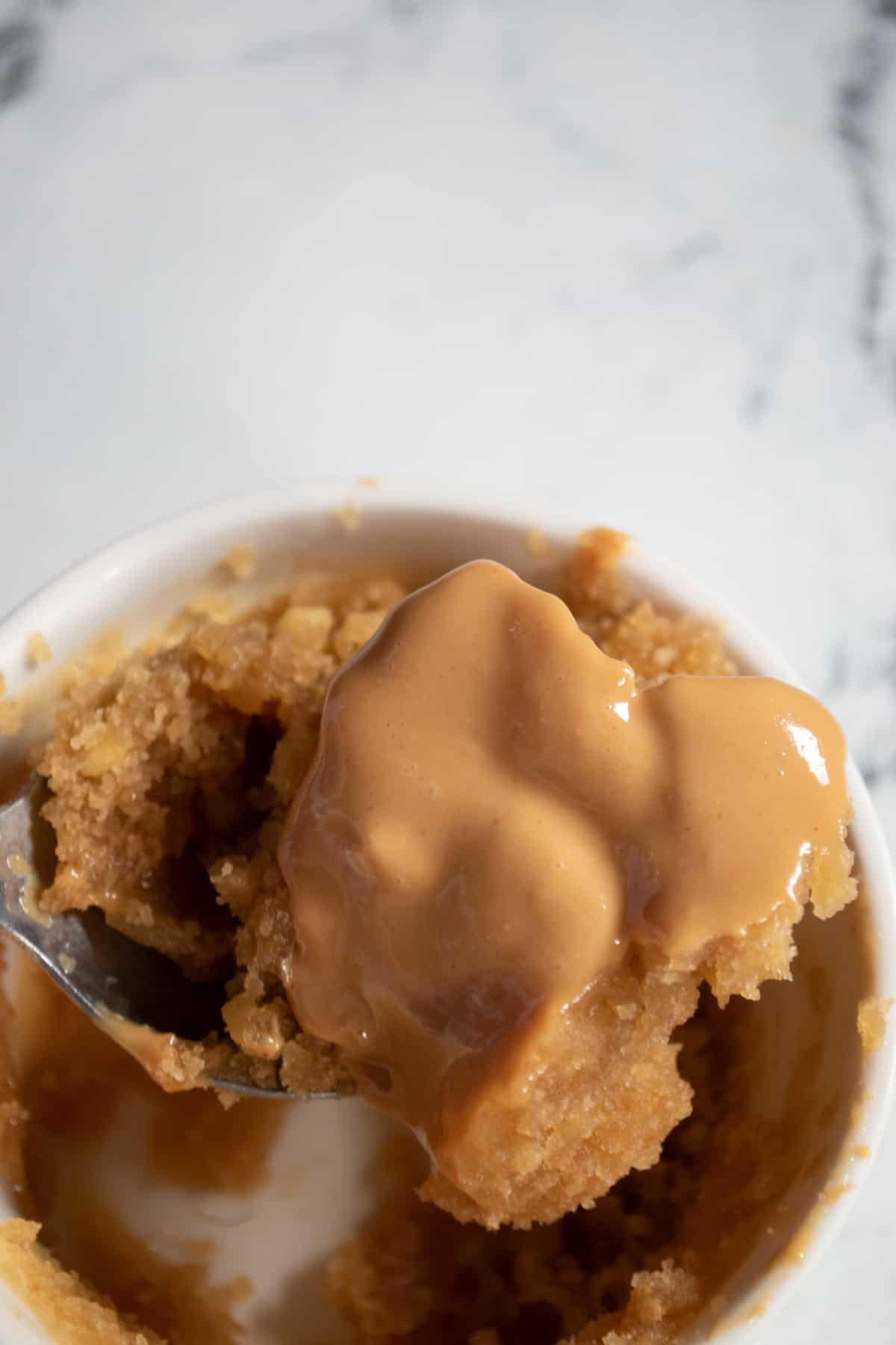 A spoonful of peanut butter mug cake with extra peanut butter. 