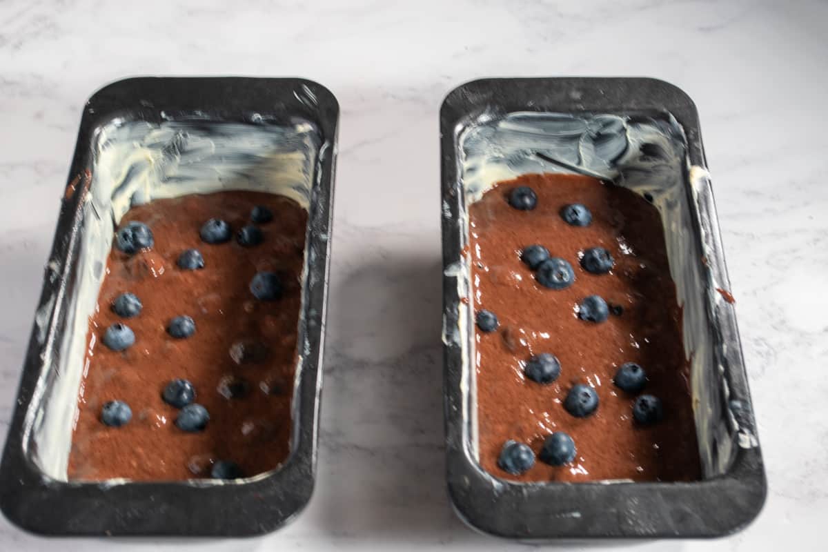 A photo of the eggless blueberry cake batter in the cake pans.
