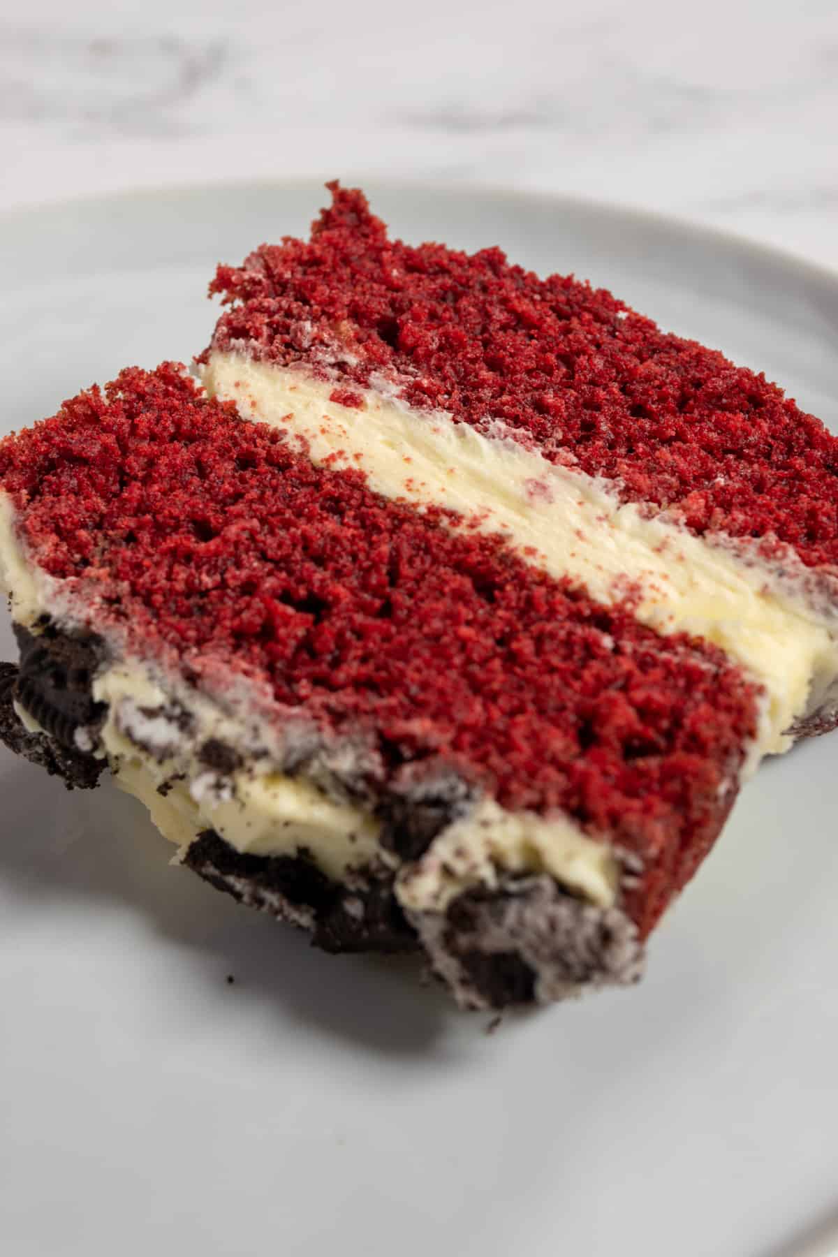 A photo of a single slice of red velvet cake at a side angle.