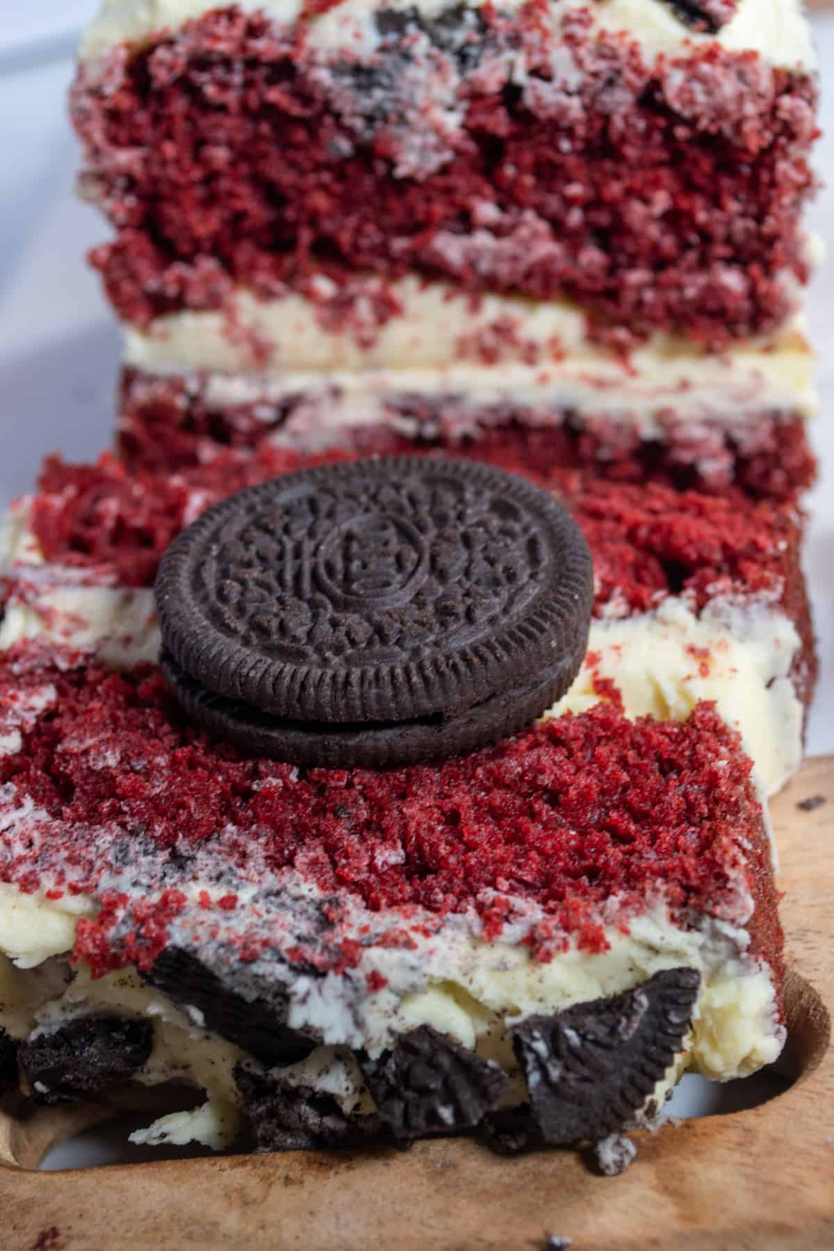 A close up shot of a slice of my eggless red velvet cake. A whole Oreo sits on top of the slice.