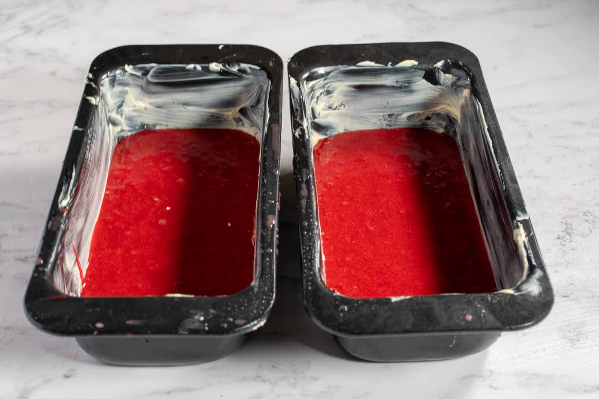 A photo of the eggless red velvet cake batter in the cake pans.