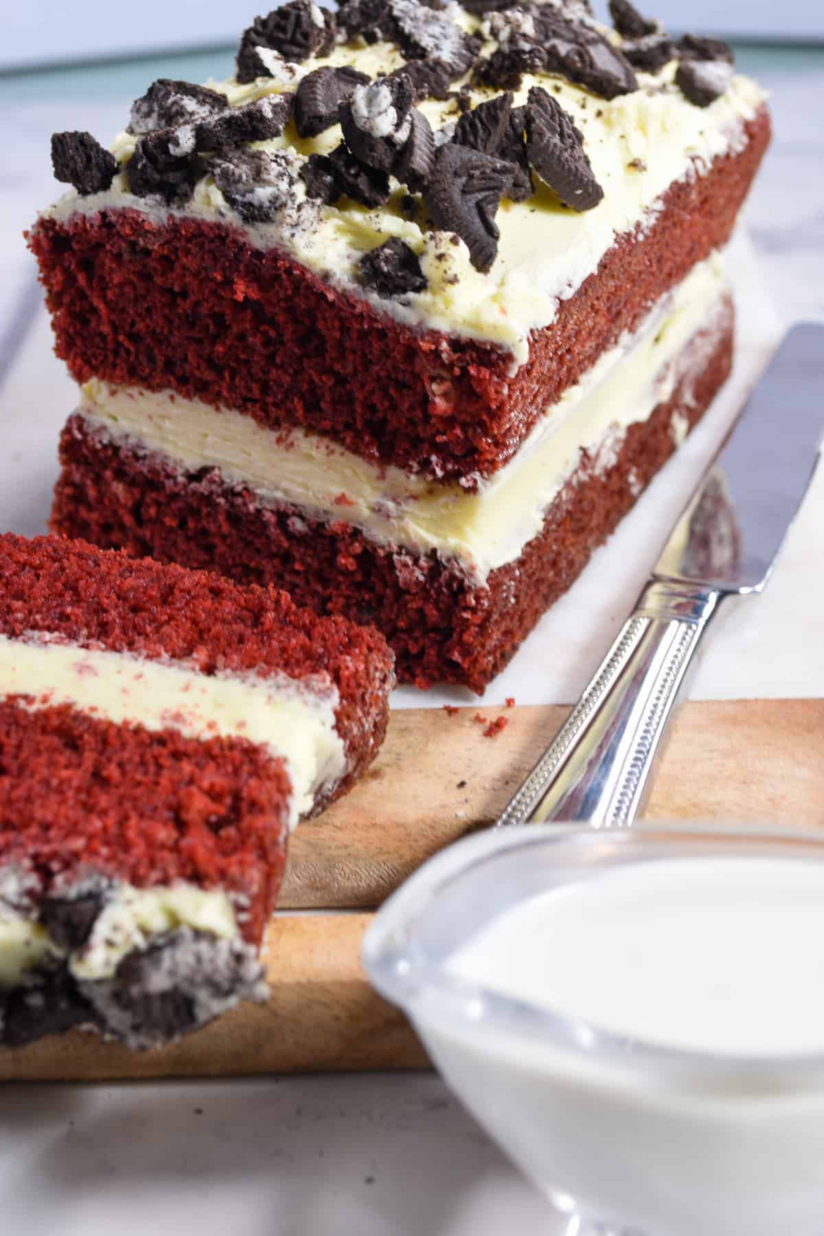 A shot of a whole eggless red velvet cake with the front sliced off.