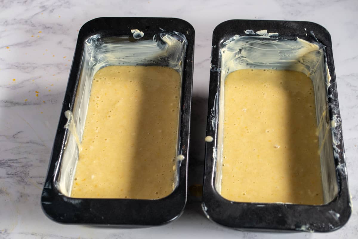 A photo of the eggless orange cake batter in the cake pans.