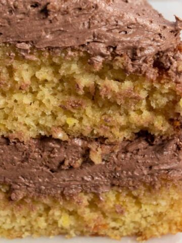 A close up shot of my chocolate lemon cake loaf. The front of the cake has been sliced so that you can see the thick layer of chocolate buttercream inside.