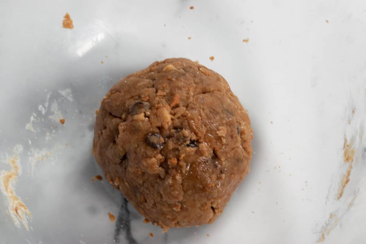 A cookie dough ball has been formed. It sits in the bowl, ready to be refrigerated. 