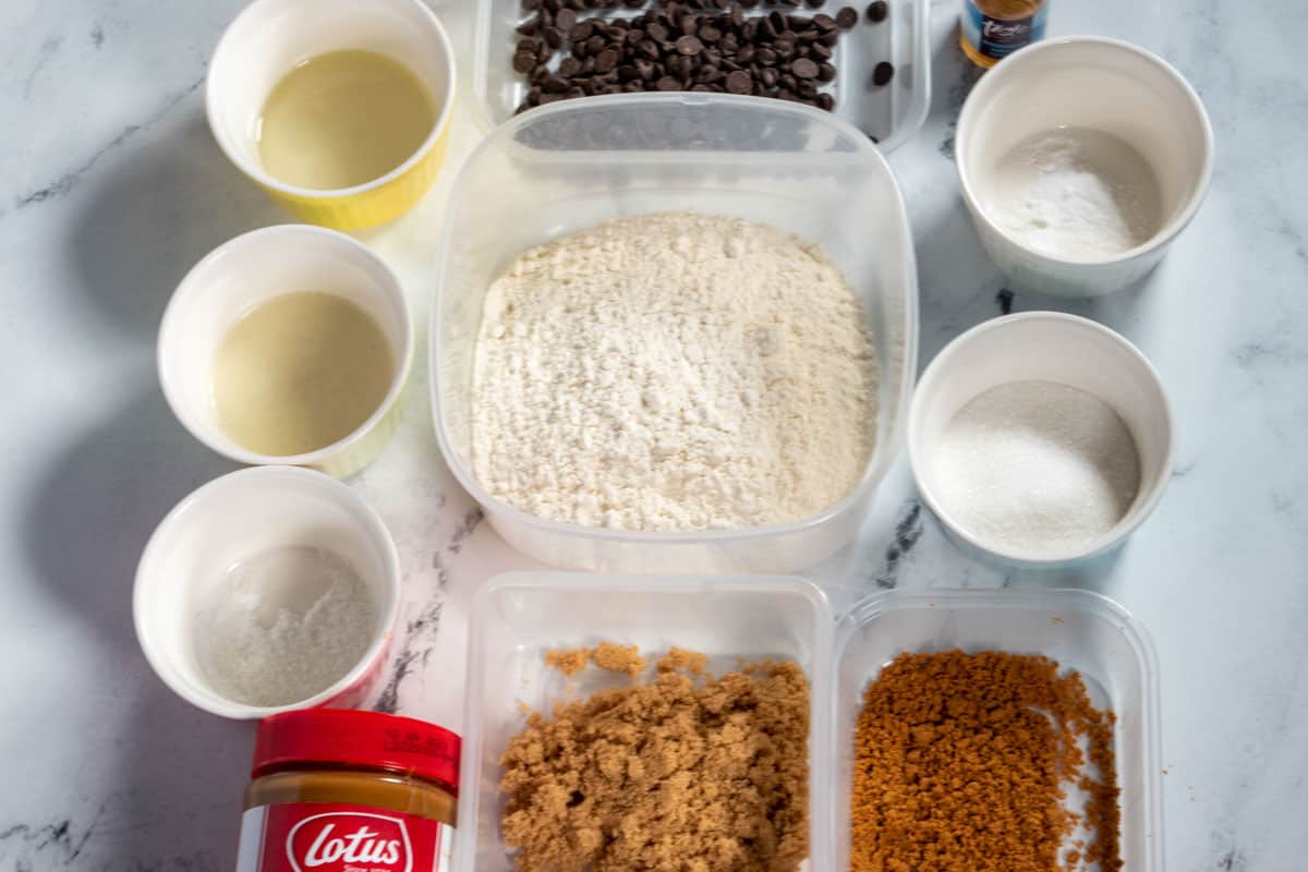 The recipe ingredients needed to make vegan biscoff cookies laid out over a white, marble background.