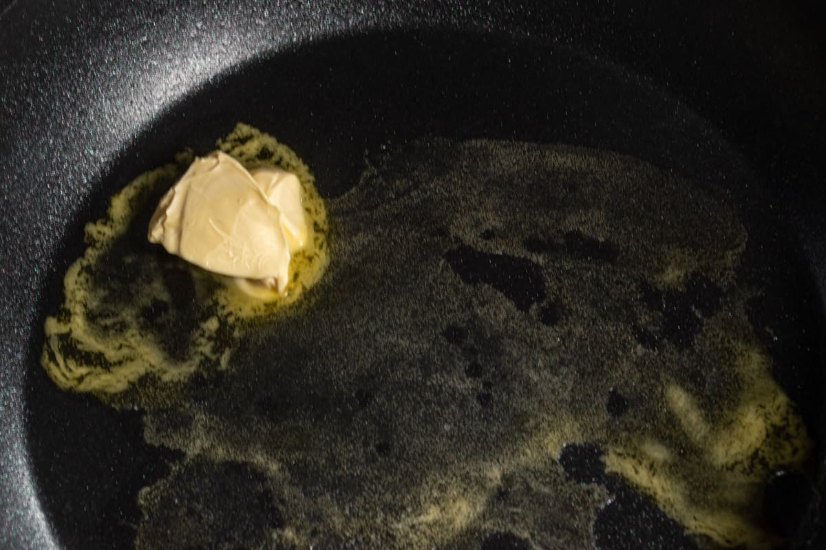 Vegan butter melting in a black pan.