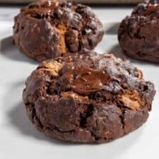 Three fudgy vegan chocolate brownie cookies on a white plate.