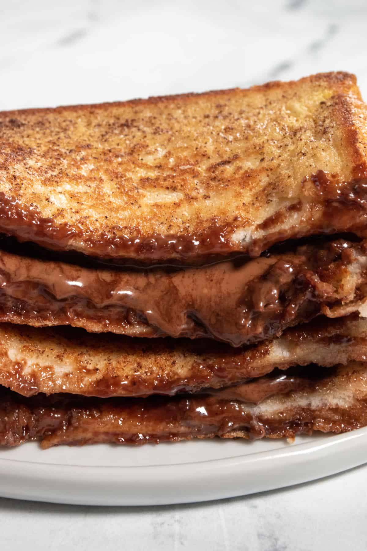 A close up shot of my vegan chocolate french toast, stacked. Thick chocolate oozes out.