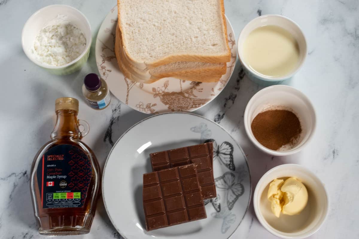 The ingredients needed to make vegan chocolate french toast laid out neatly over a white marble background. 