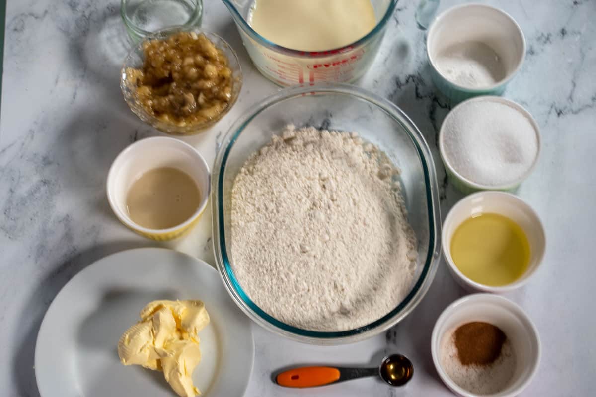 The ingredients needed for my vegan cinnamon muffins laid out neatly over a white, marble background.