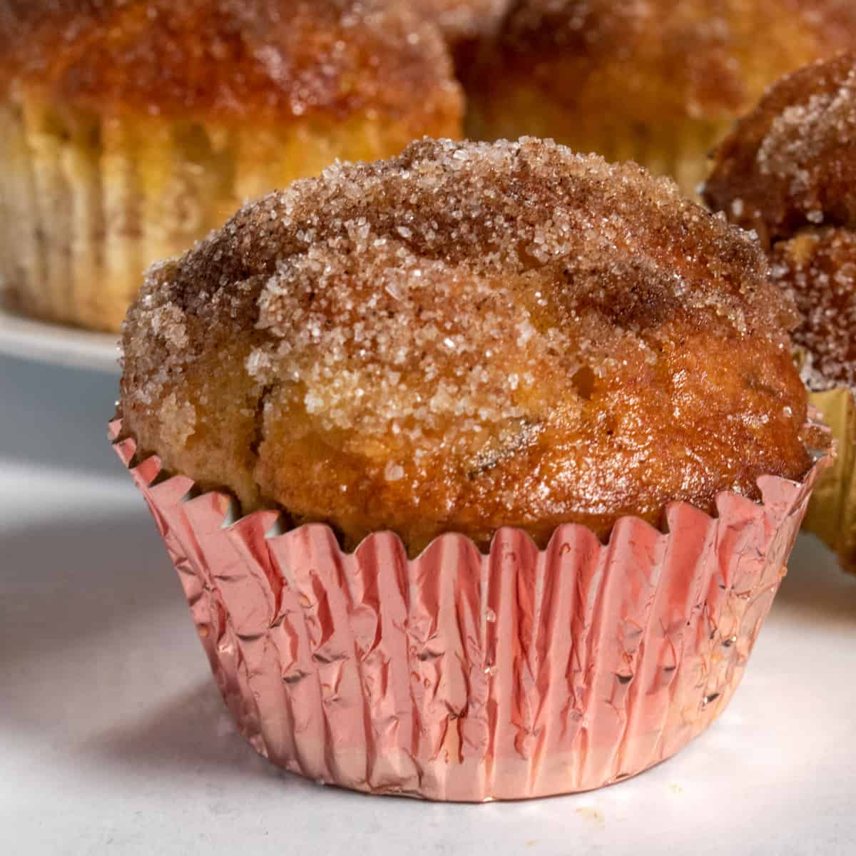 A close up photo of light and fluffy vegan banana muffins, coated in a sweet cinnamon sugar. 