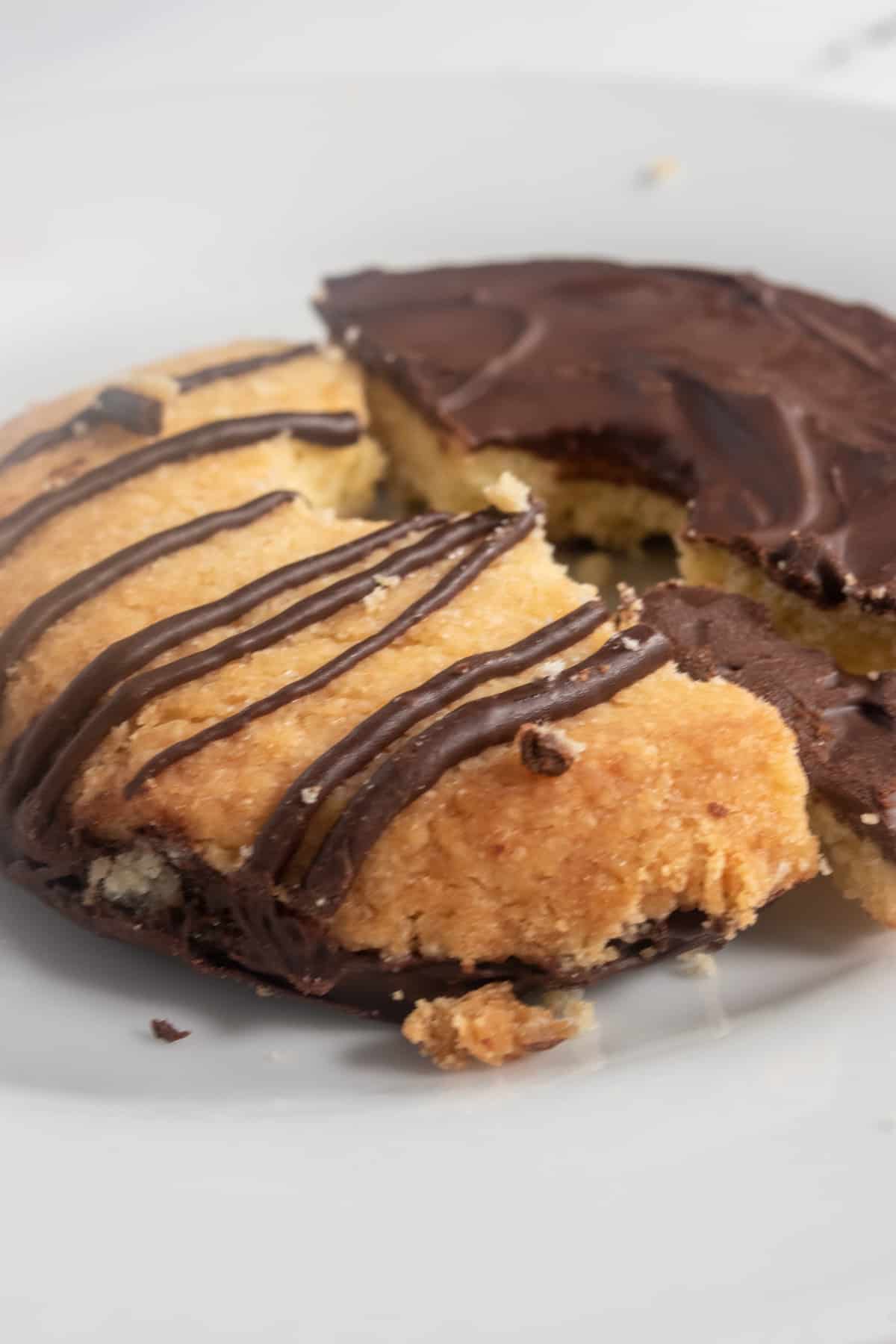 A crumbly cookie broken in half. One of the halves is upside down, revealing the chocolate bottom.