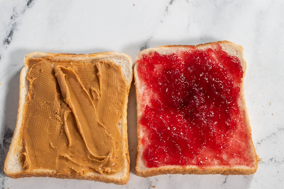 The peanut butter and jelly spread on two slices of white bread.