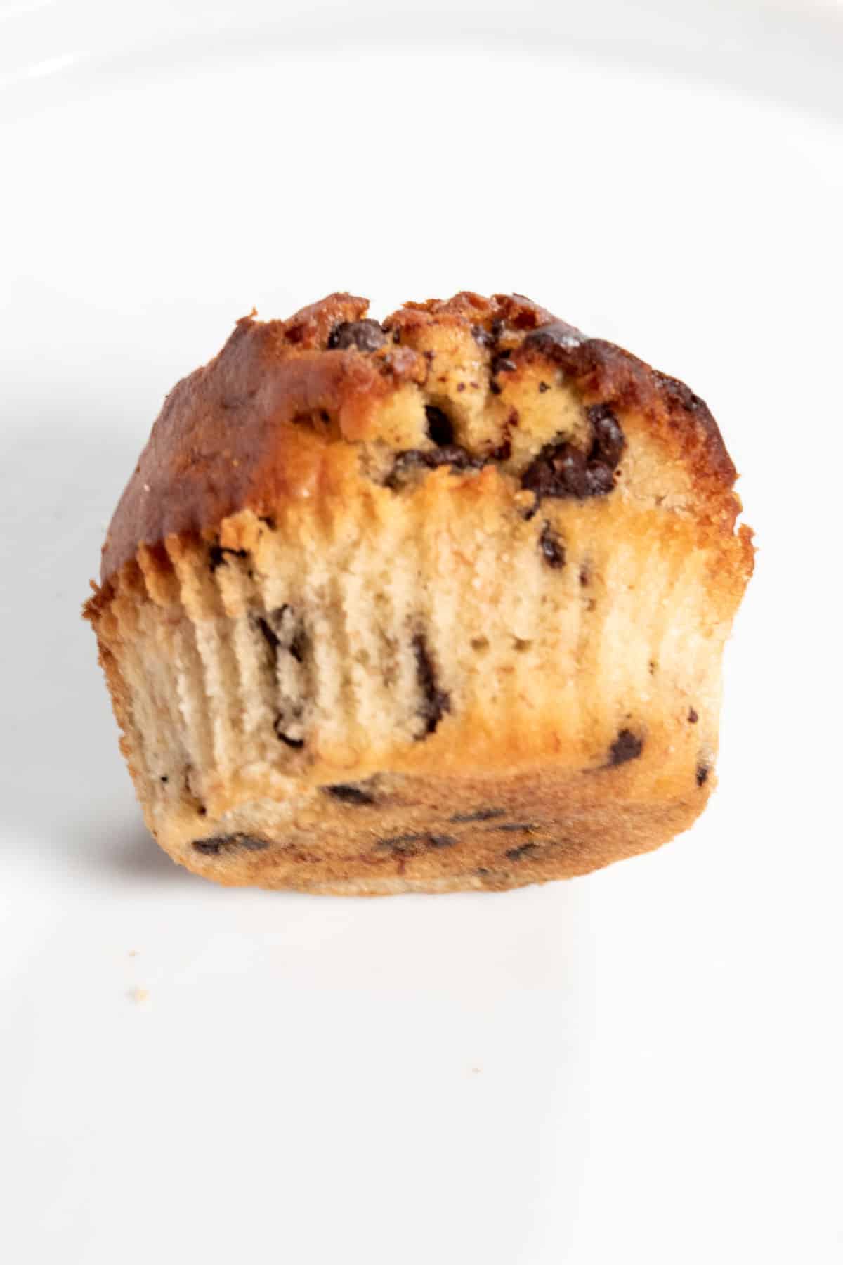 A whole muffin led on its side over a white backdrop. It is golden brown.