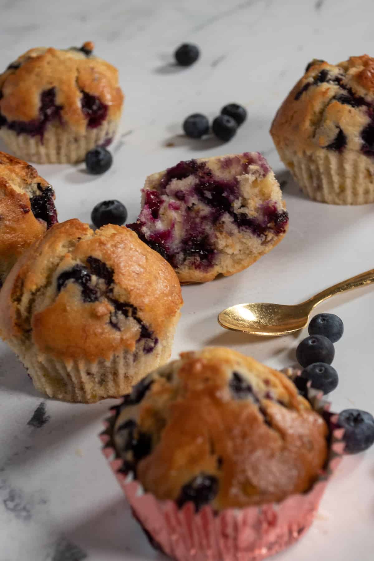 A shot of several muffins and that golden spoon again. Loose blueberries also on display. 