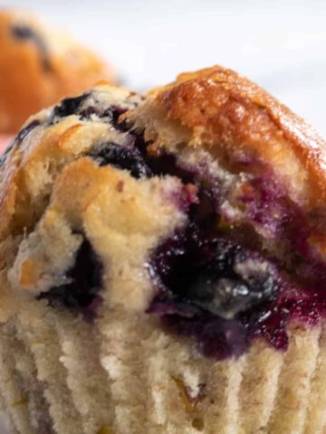 A close up photo of one of my vegan pistachio muffins with blueberries. The blueberries look super juicy.