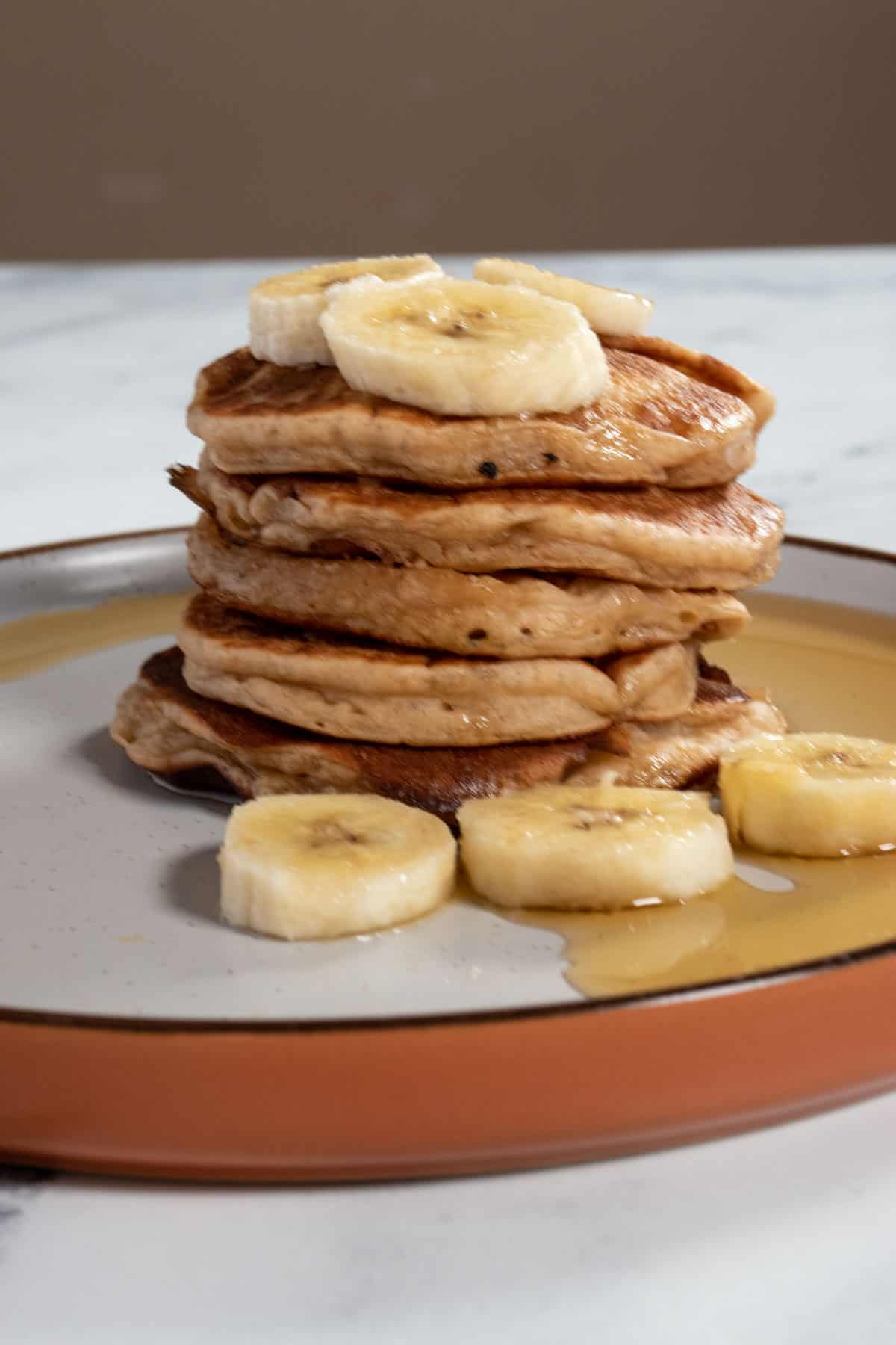 A stack of my vegan protein pancakes, drizzled with maple syrup.