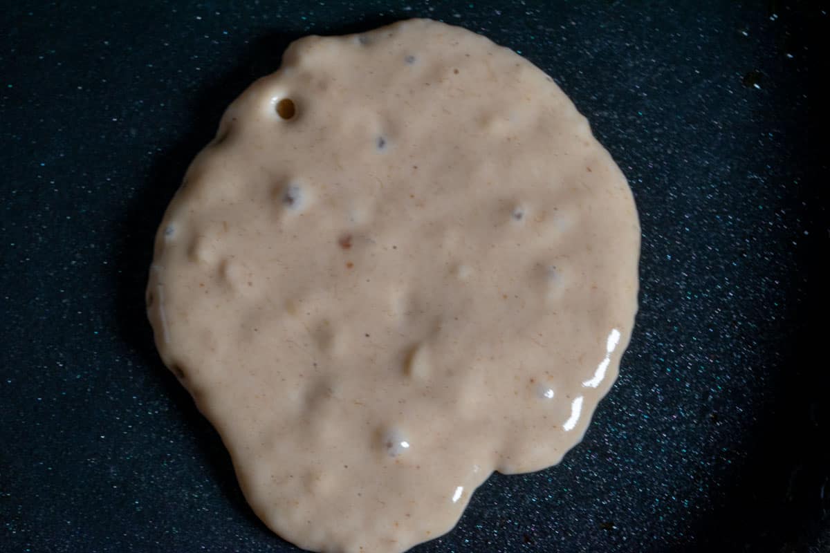 Pancake batter bubbling in the pan. 