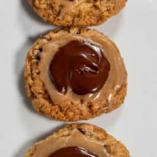 Three golden brown vegan twix cookies lined up vertically on a white plate.