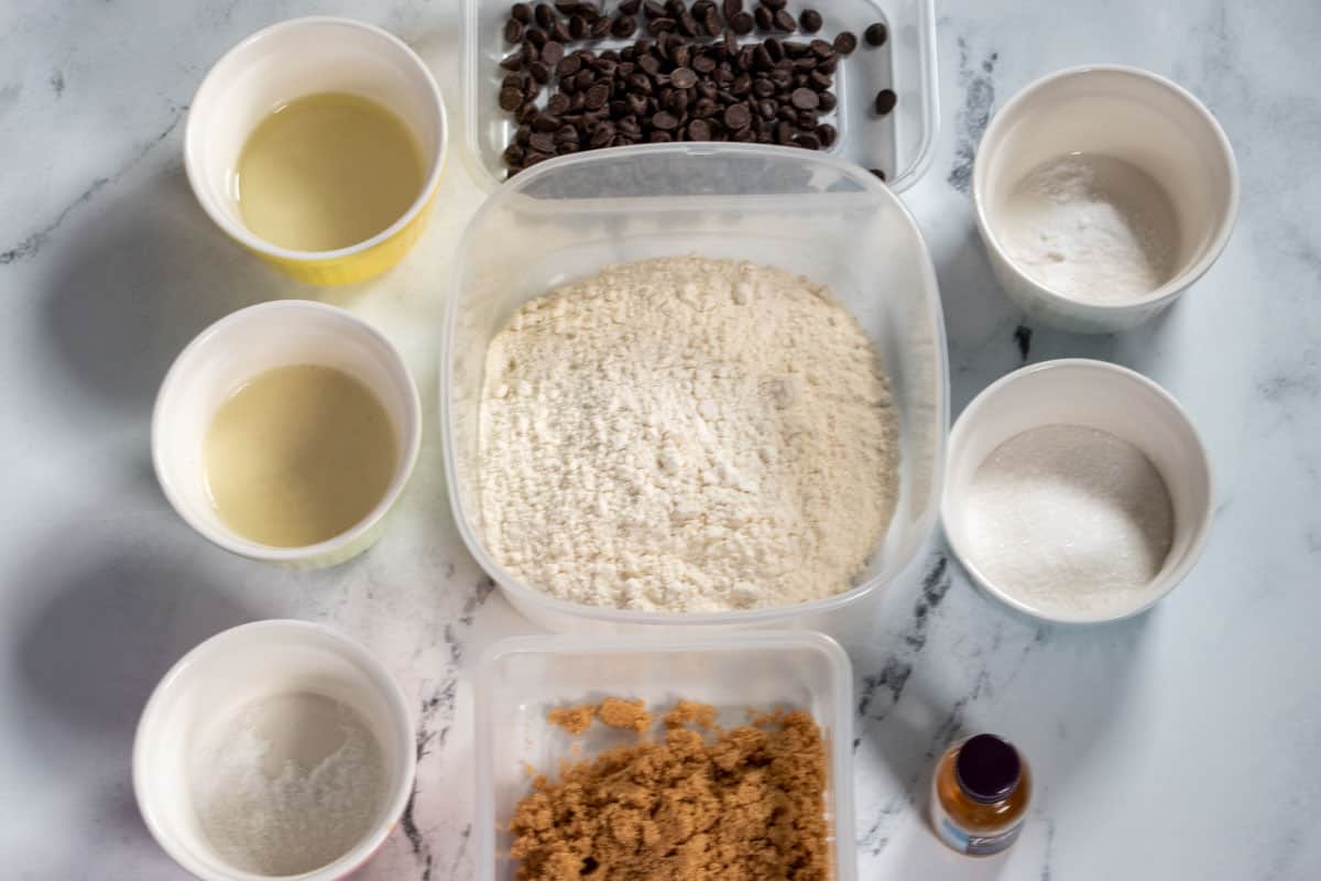 The ingredients needed to make vegan twix cookies laid out neatly over a white, marble background.