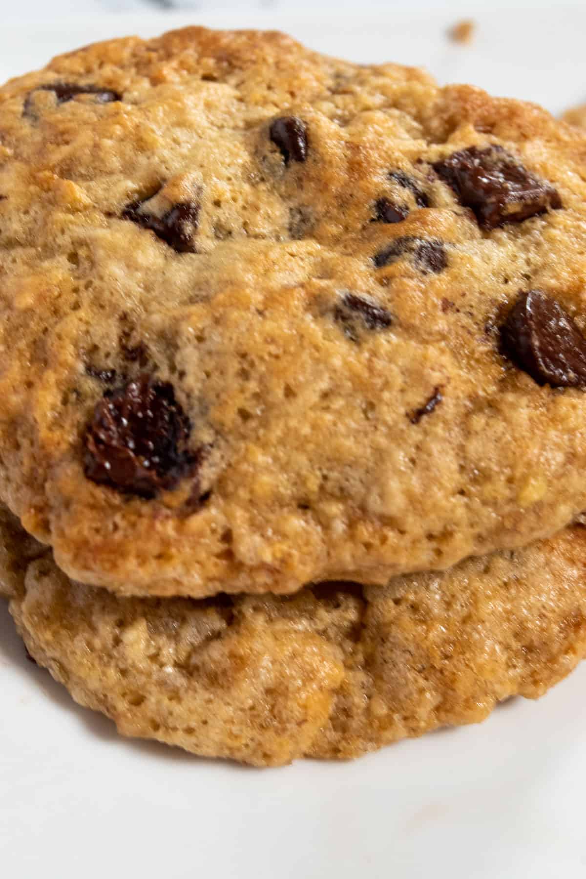 A close up shot of two vegan banana chocolate chip cookies, stacked. The chocolate chips on top look melty.