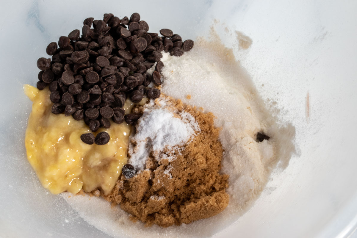 The mashed banana and the dry ingredients in a large mixing bowl ready to be combined.