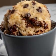 My vegan banana mug cake being spooned out from a grey mug. The chocolate chips are melted inside.