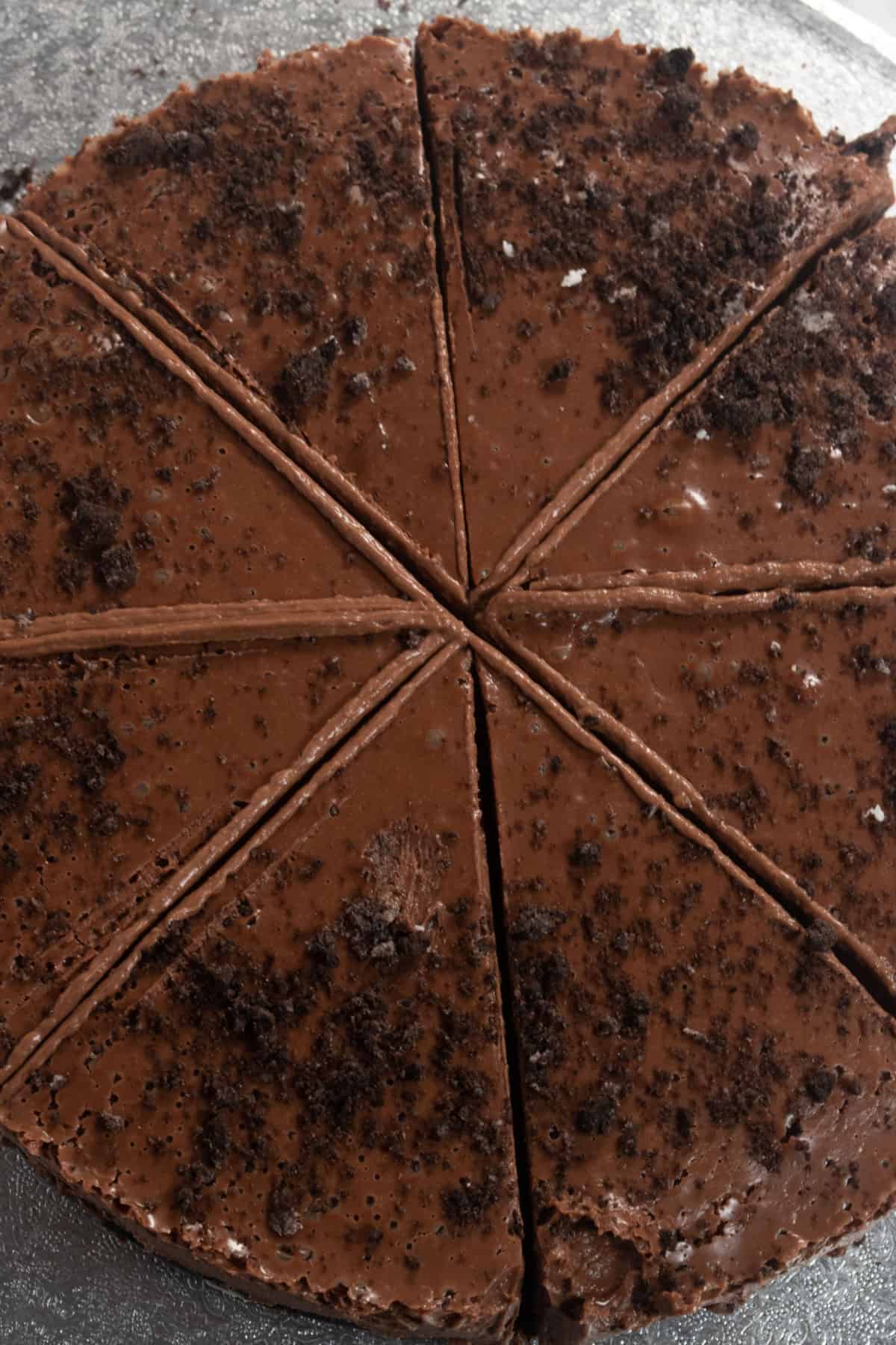 An overhead shot of an entire vegan chocolate cheesecake. It is equally sliced into eight pieces. 