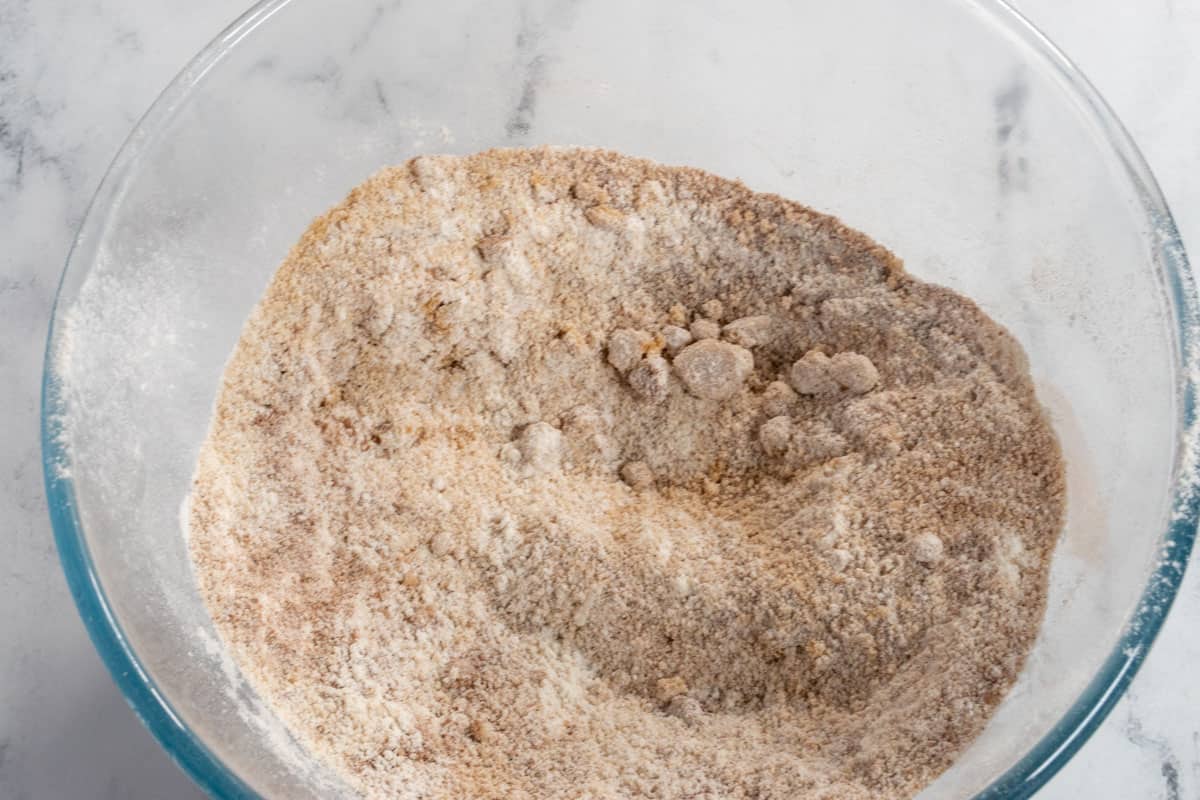 The dry ingredients for the cinnamon cake combined inside a large, glass bowl. 