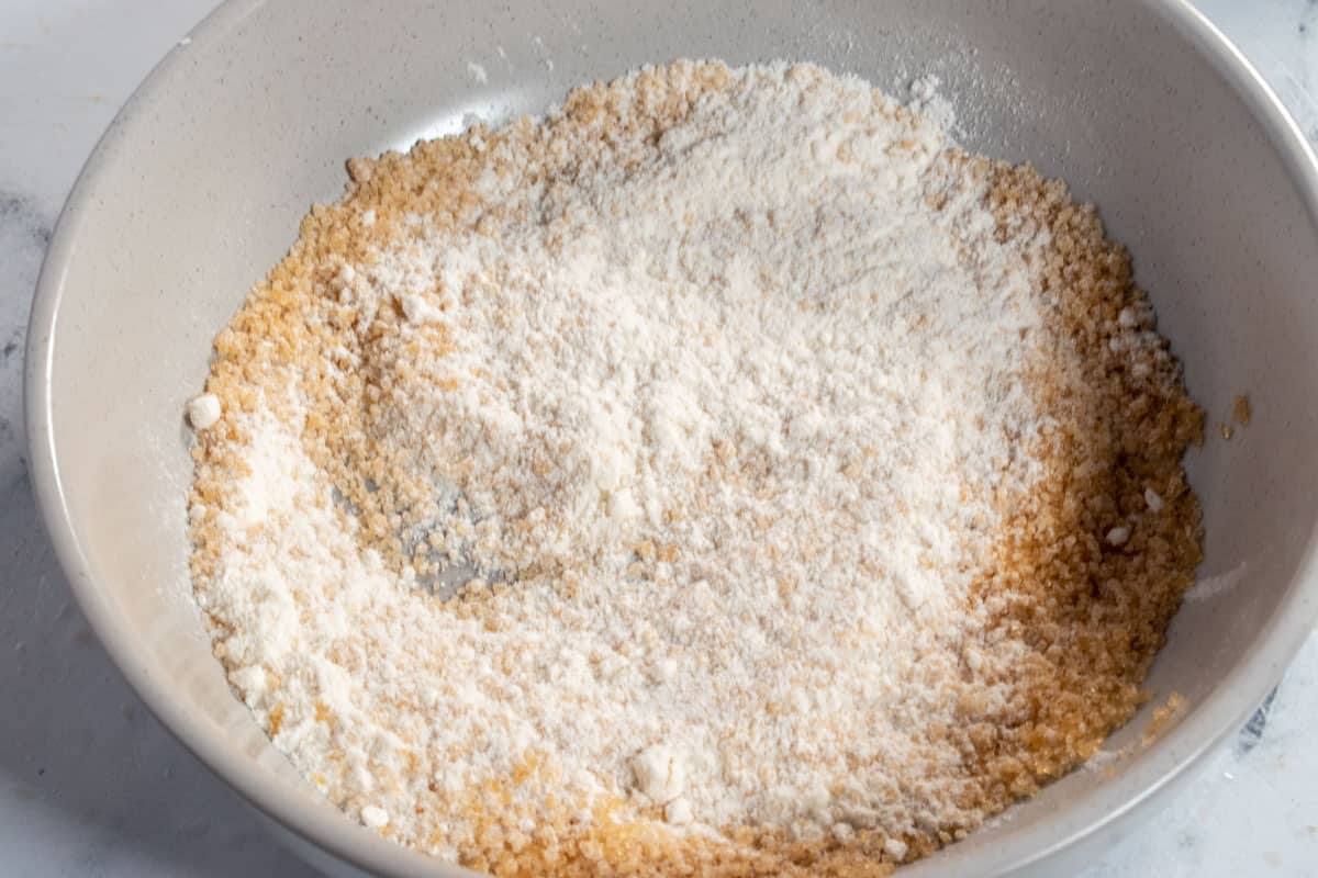A photo of flour and brown sugar combined in a small, grey bowl. This is for the streusel.