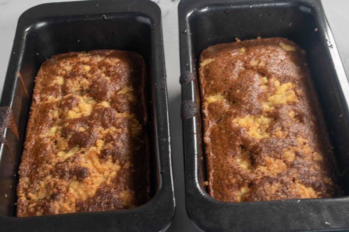 Two baked cakes inside their cake tins cooling down. 
