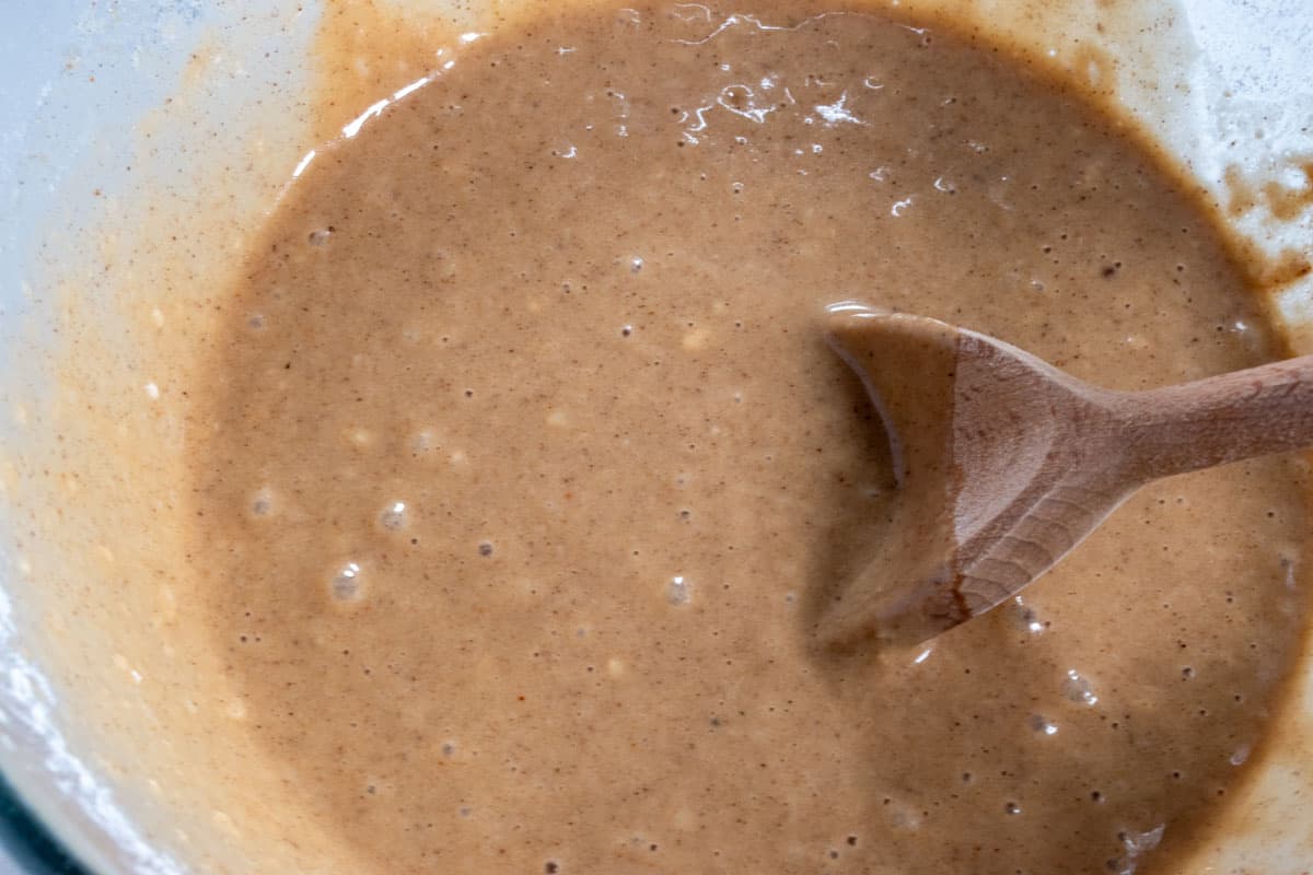 The dry ingredients have been folded into the wet, creating a light brown gingerbread cake batter.