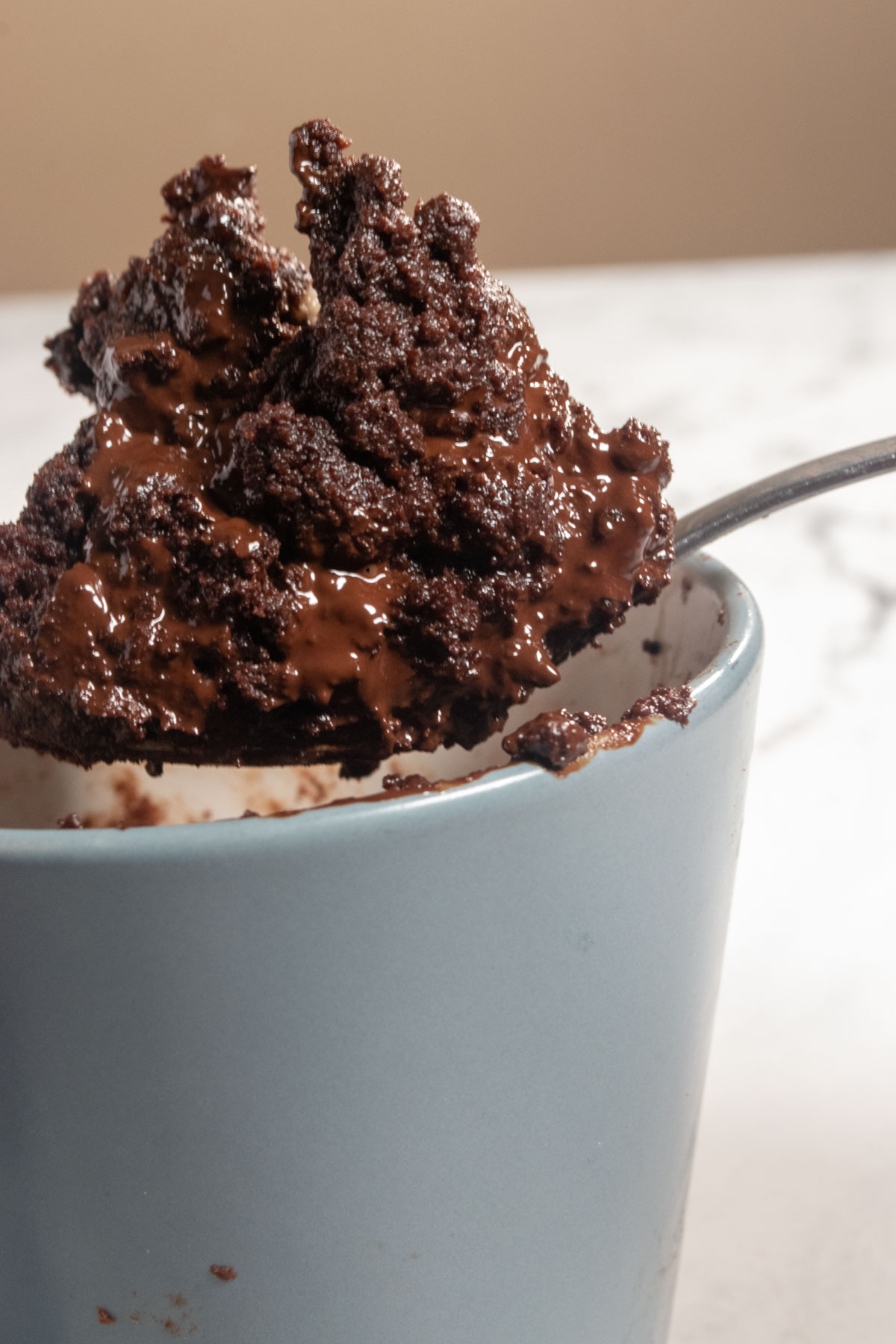 Lots vegan mug brownie balancing on a silver spoon.