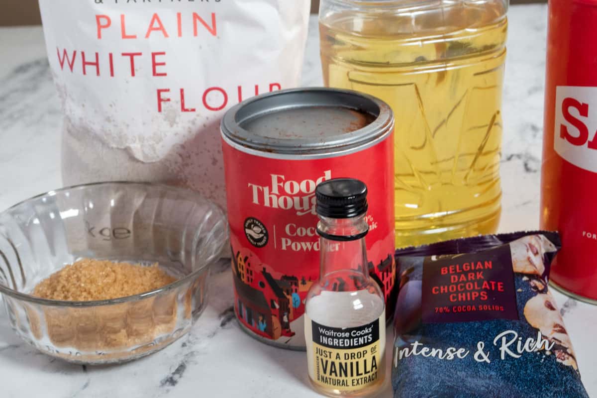 The ingredients that you will need to make a vegan mug brownie laid out over a white, marble backdrop. 