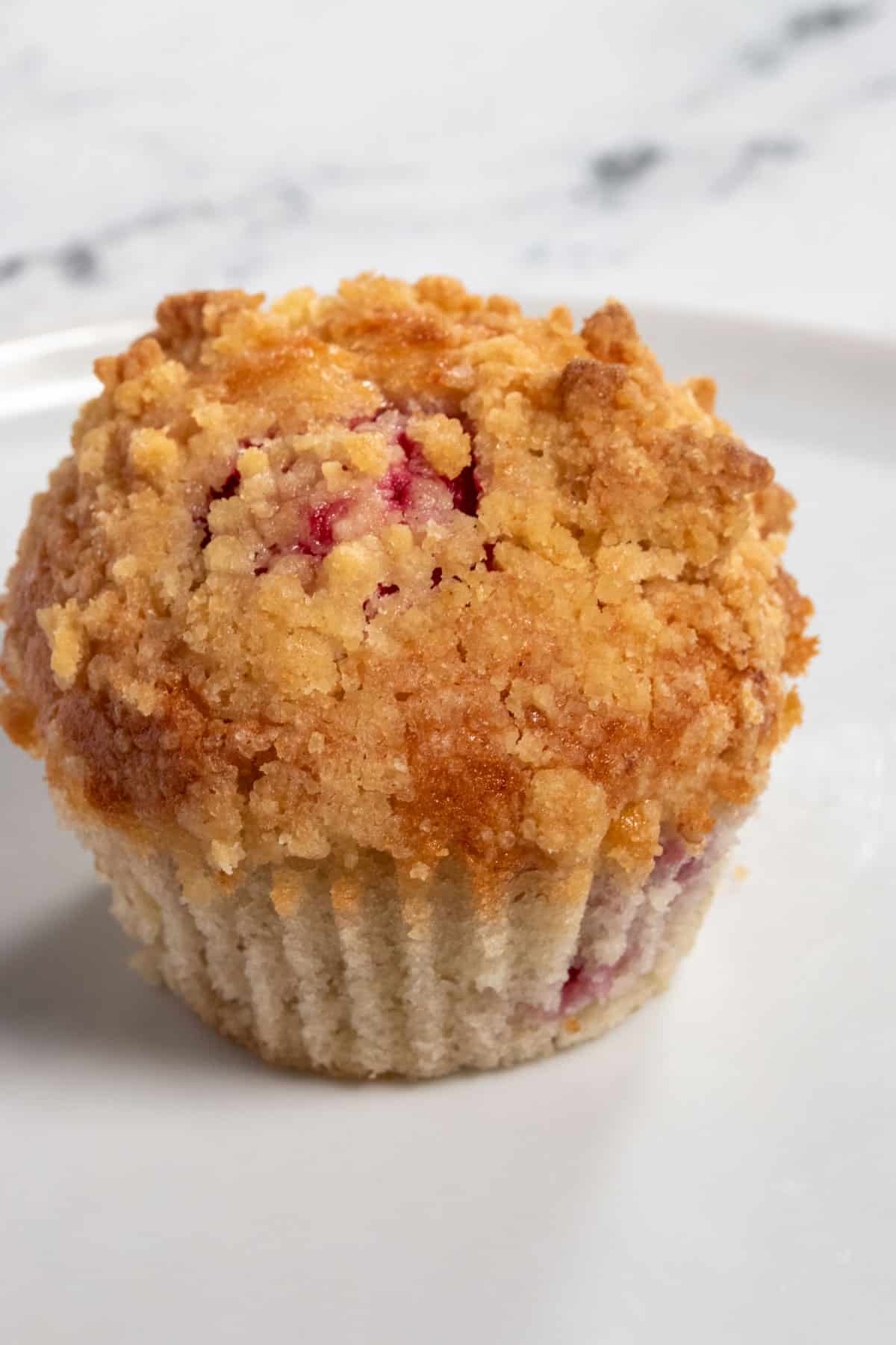 A zoomed in shot of a case-less raspberry muffin. The lighting is bright, showcasing the bright pink colours inside.