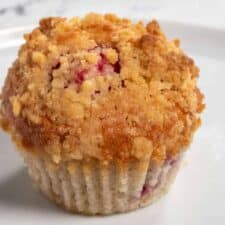 A close up shot of one of my vegan raspberry muffins. The streusel on top is golden brown.