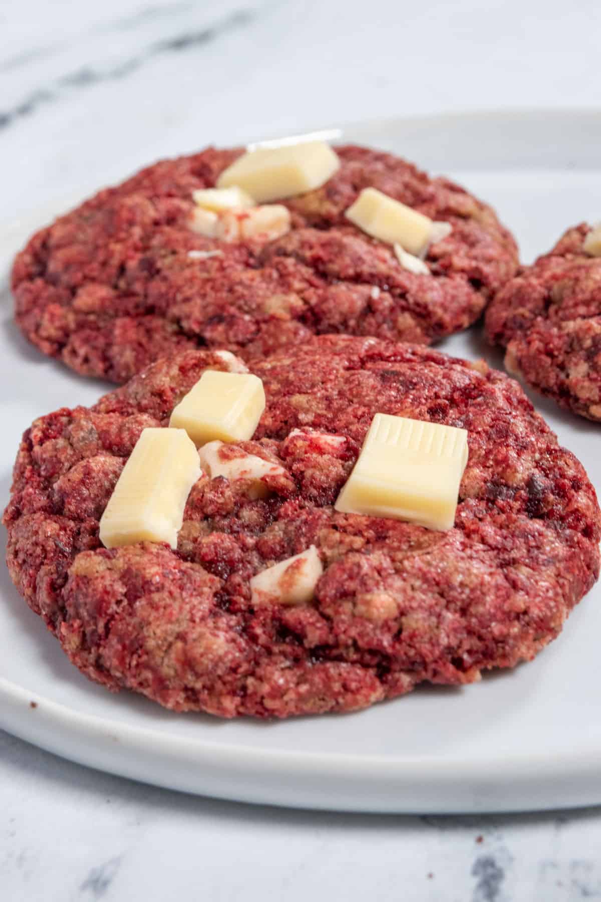 Some red velvet cookies scattered on a white saucer, waiting to be eaten. 