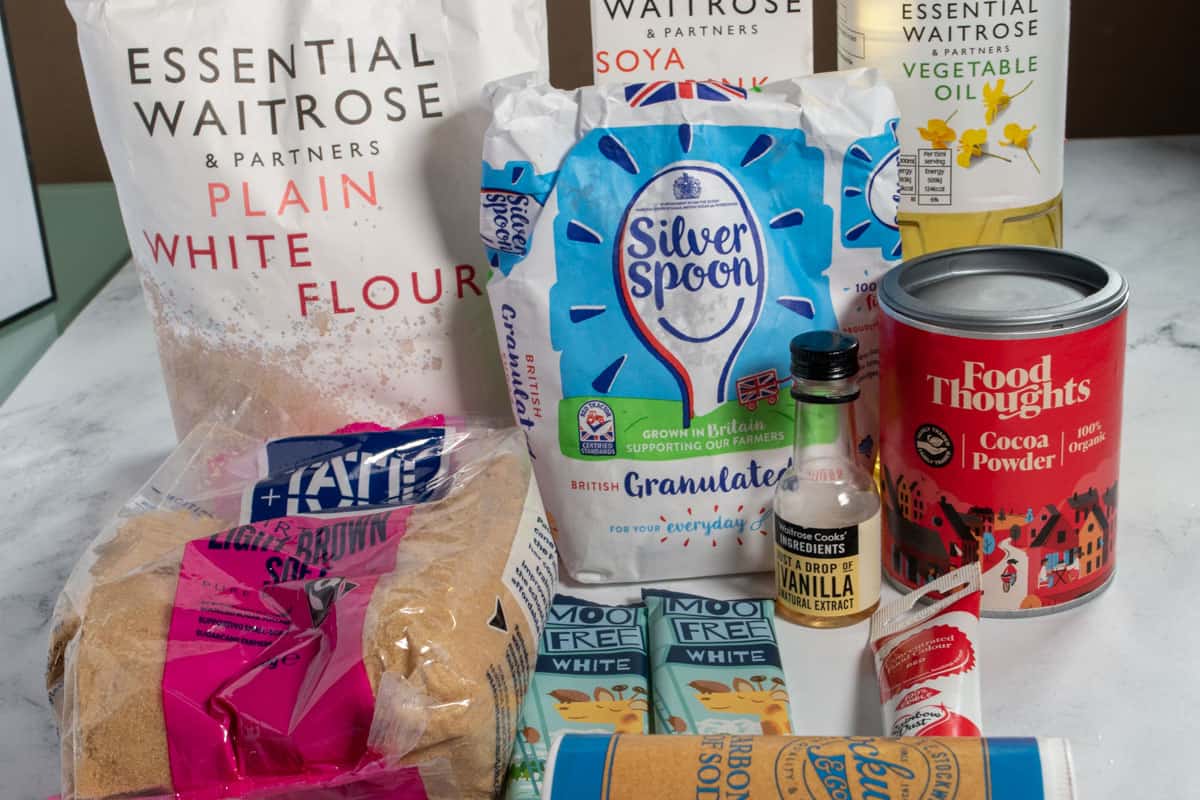 The ingredients that you will need for my vegan red velvet cookies laid out over a white, marble backdrop. 