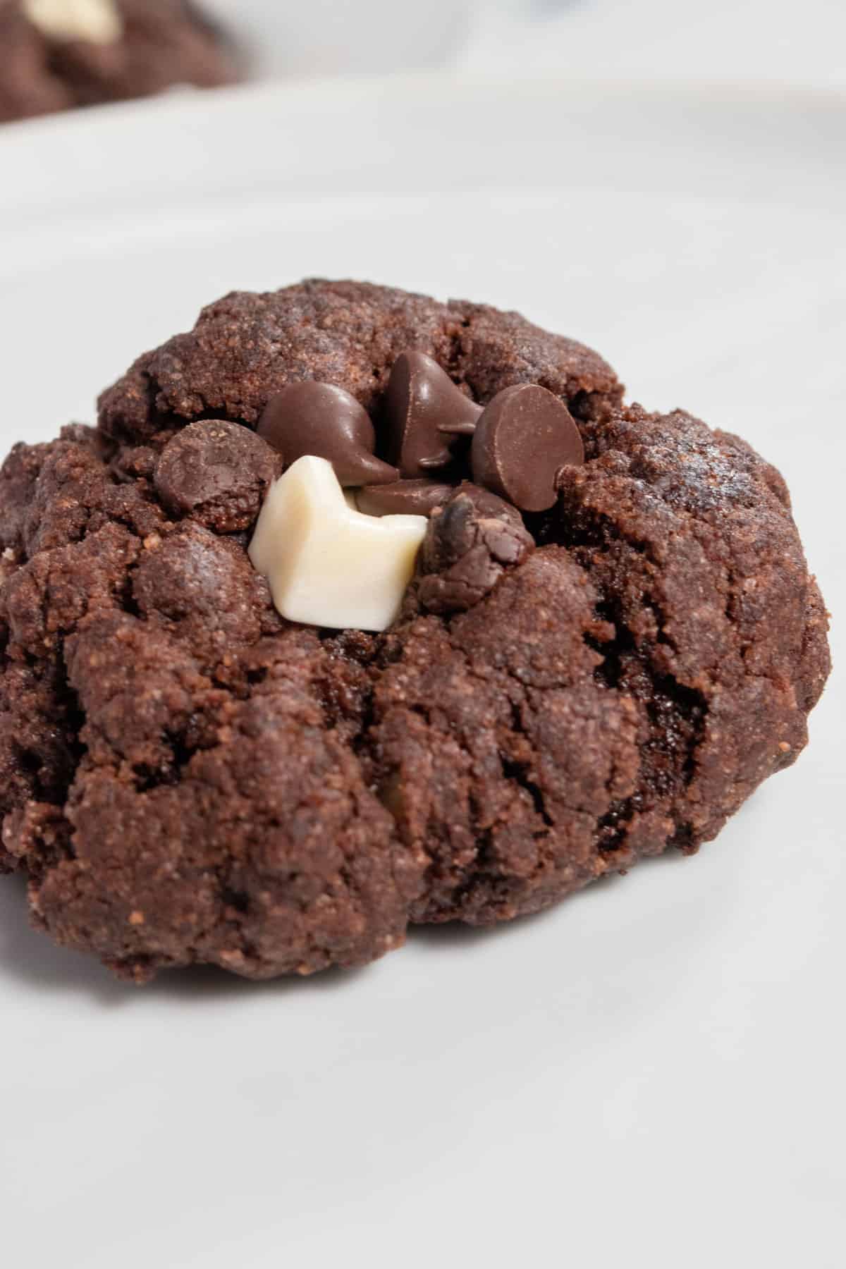 A close up shot of one, chunky cookie. It has both vegan dark chocolate and vegan white chocolate on top.